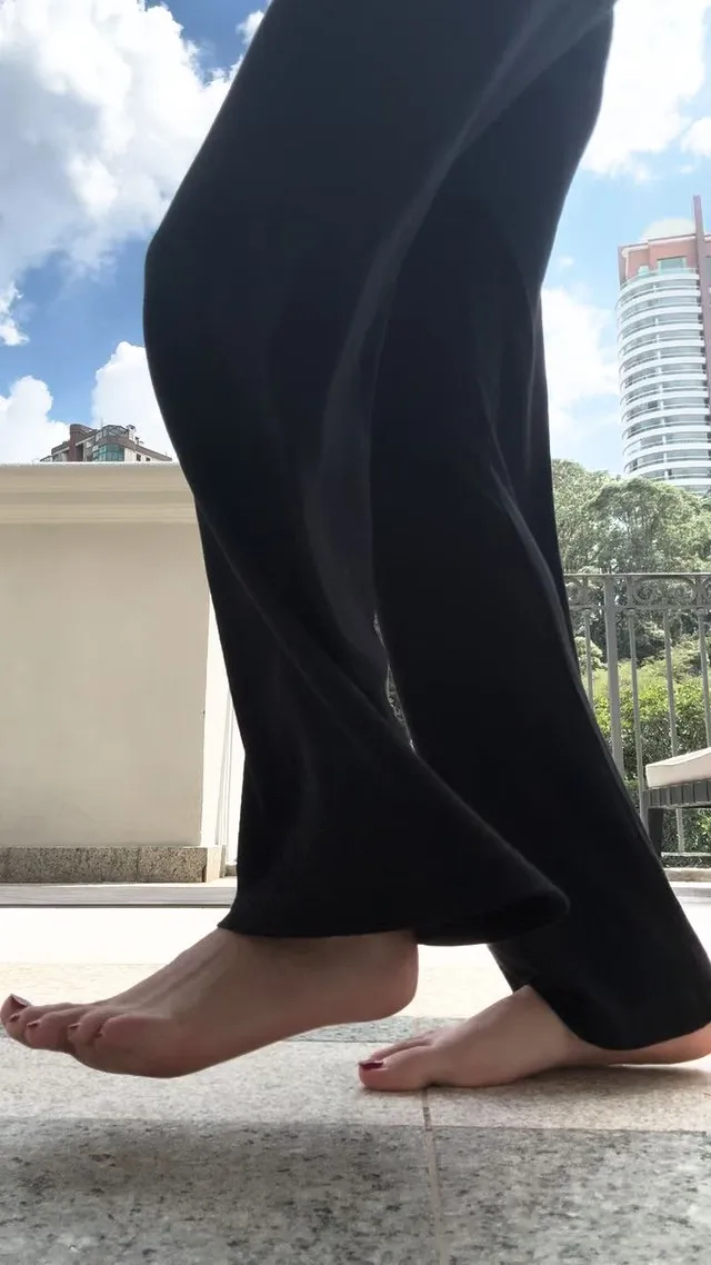 Olivia Rodrigo standing outdoors in dark trousers.