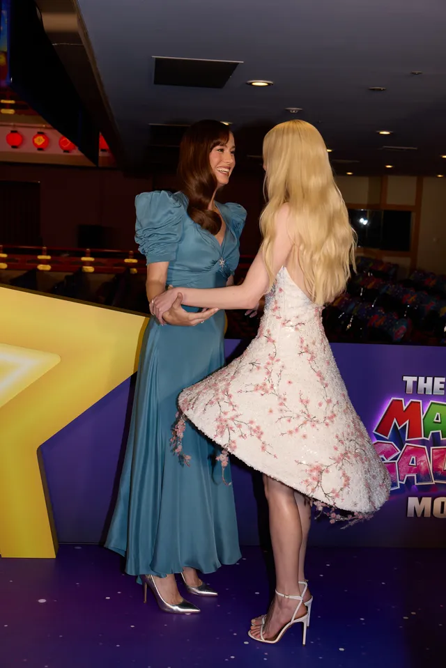Anya Taylor-Joy posing beside another guest in a floral dress and strappy heels.