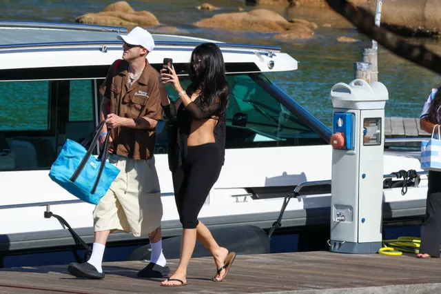 Kylie Jenner walking beside a boat in flip-flops.