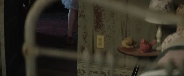 Chloë Grace Moretz sitting barefoot indoors in a screen image.