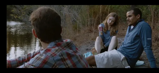 Willa Fitzgerald sitting barefoot beside a pond in a scene.