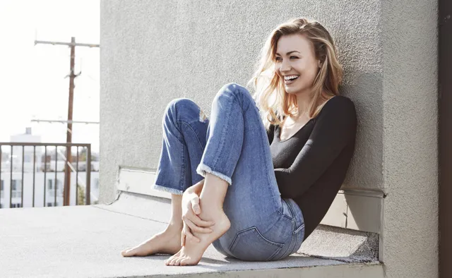 Yvonne Strahovski sitting outdoors in jeans and a dark top.