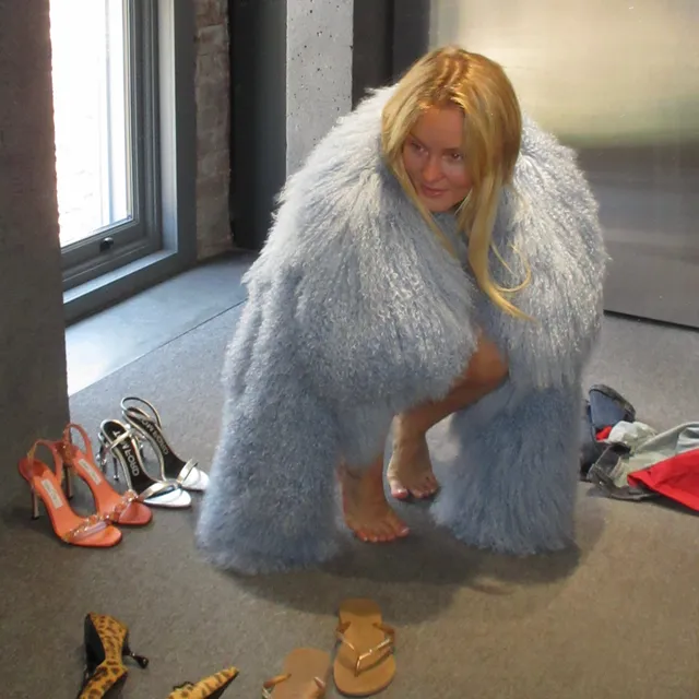 Zara Larsson crouching barefoot in a pale blue coat.
