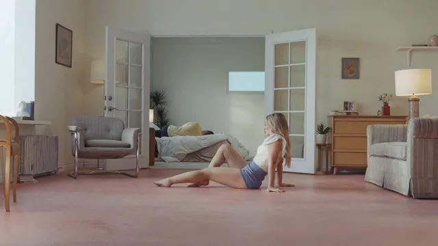 Hilary Duff sitting barefoot on a carpet in a sunlit room.