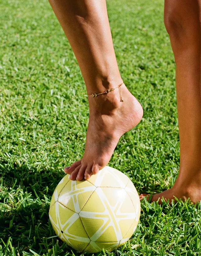 Taylor Hill resting a bare foot on a ball on grass.