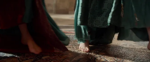 Daisy Ridley standing beside another character in a screen scene.