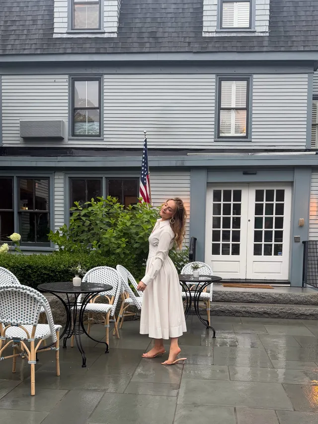 Elizabeth Gillies standing outdoors in a pale dress.