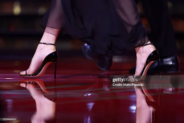 Anya Taylor-Joy wearing black pointed heels beneath dark trousers.