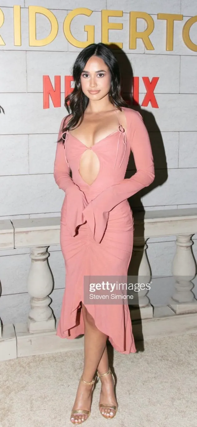 Emily Tosta wearing a pink dress and clear heels at an event.