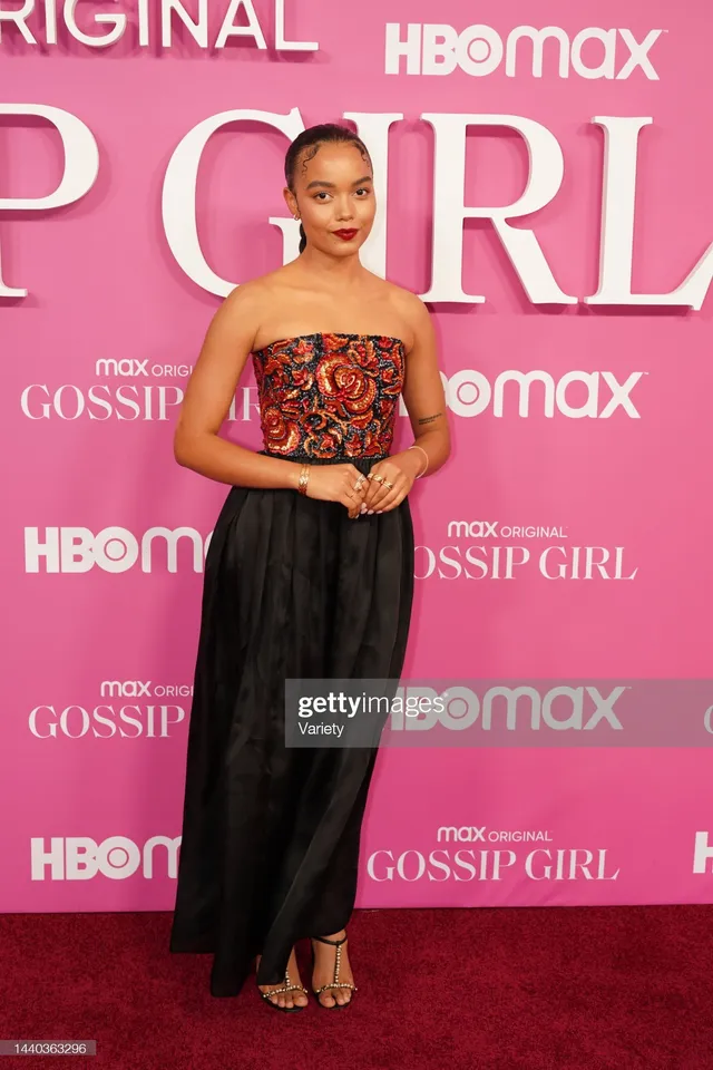 Whitney Peak wearing an embellished top, long black skirt and gold heels at a premiere.