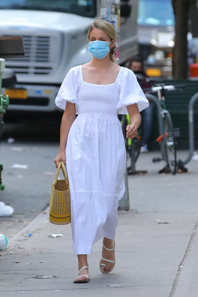 Dianna Agron walking on a city pavement with a woven bag.