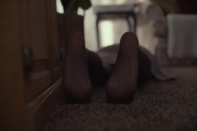 Daisy Ridley lying on a carpet beside a wall in a screen scene.