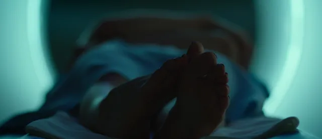 Chloë Grace Moretz lying with bare soles visible in a blue-lit screen image.