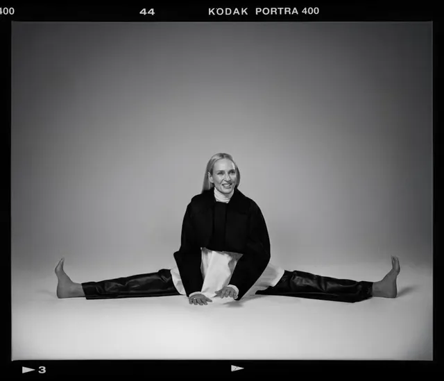 Uma Thurman sitting barefoot in a black outfit.