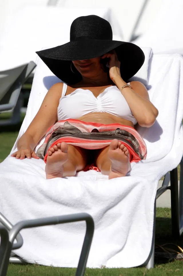 Sofía Vergara reclining on a sunlounger with her bare soles facing forward.