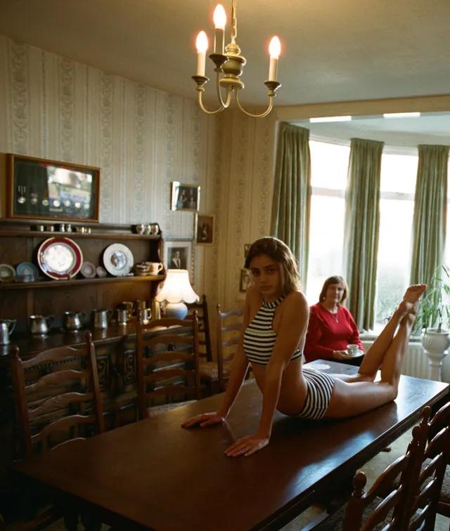 Taylor Hill sitting barefoot on a table during an indoor photograph.