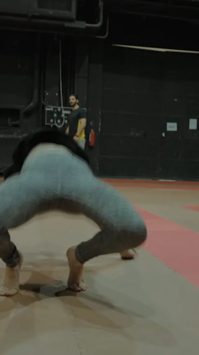 Emma Myers bending forward barefoot during gym training.