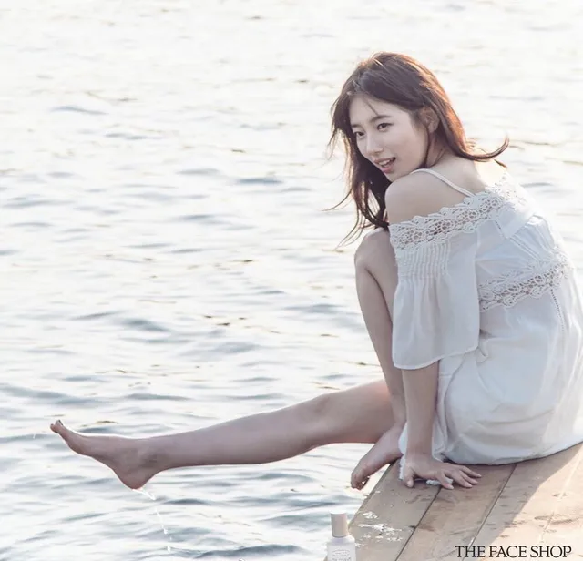 Bae Suzy sitting barefoot on a dock.