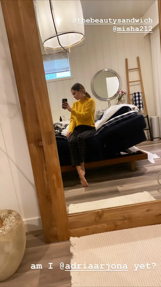 Debby Ryan sitting in a yellow top in a mirror view.