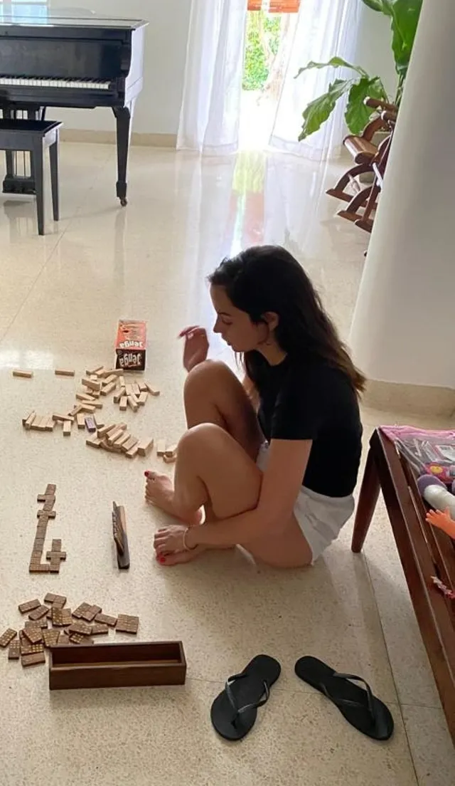 Ana de Armas sitting on a floor beside game pieces.
