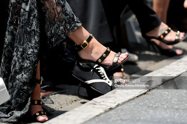 Miley Cyrus wearing black multi-strap heels beneath a long dress.