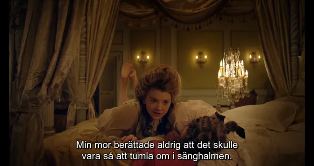 Natalie Dormer sitting in an ornate bed in a screen scene.