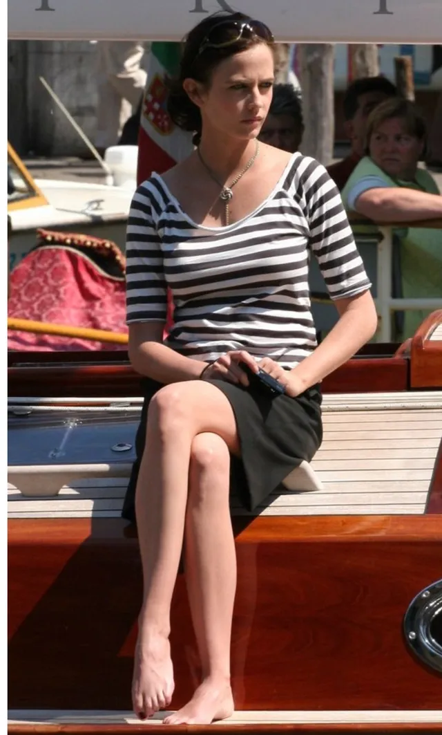 Eva Green sitting barefoot beside the water on a boat.