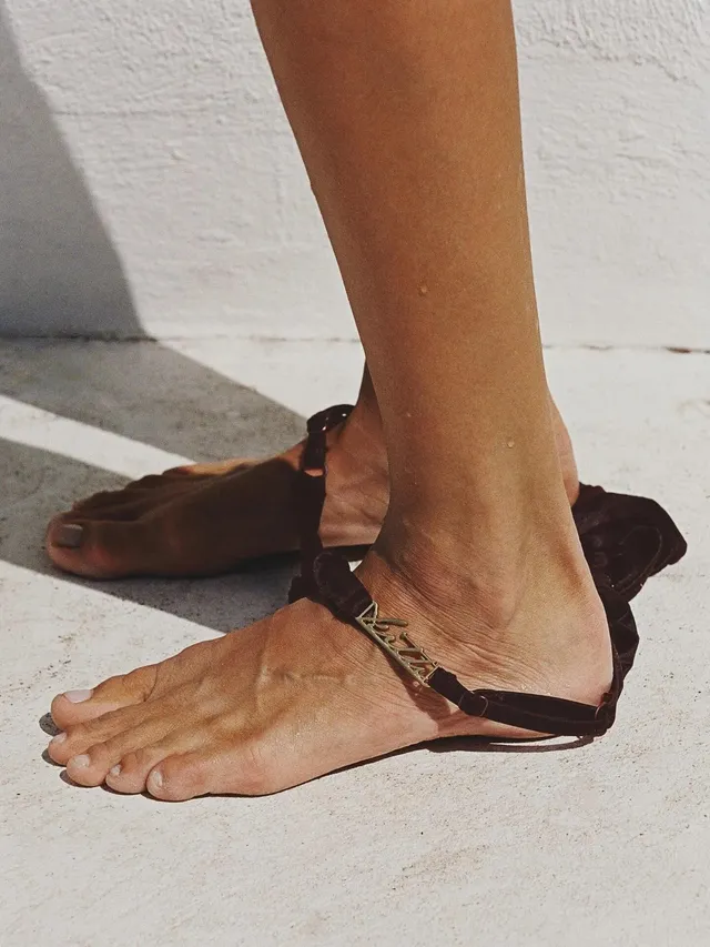 Josephine Skriver wearing flat leather sandals on a pale surface.