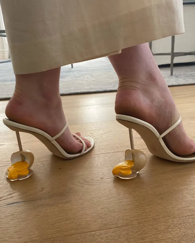 Elle Fanning wearing white high-heeled sandals with decorative yellow heels.