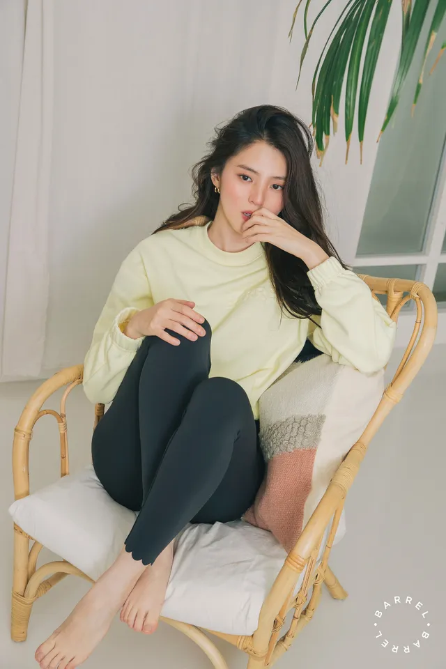 Han So-hee sitting barefoot in a wicker chair.