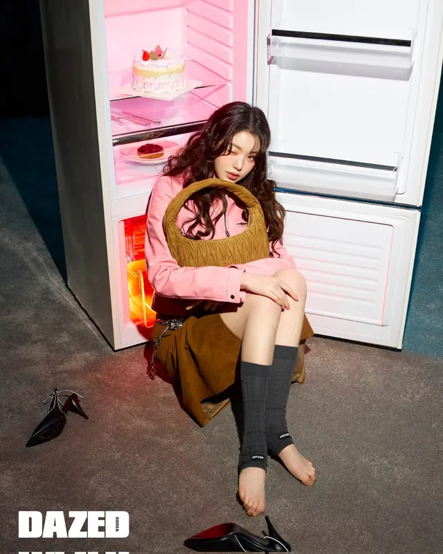Jang Wonyoung sitting with bare toes visible beneath dark leg warmers.