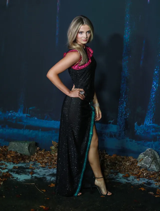 Freya Allan wearing a dark gown and heeled sandals at a premiere.