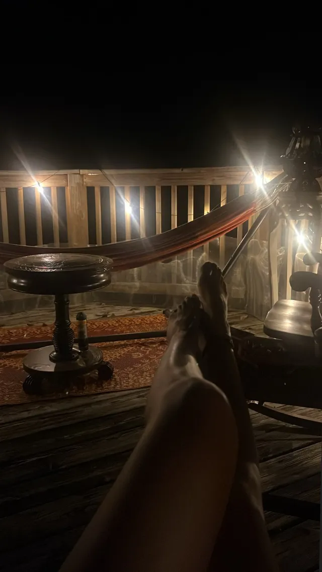 Grace VanderWaal resting bare feet near a candlelit table.