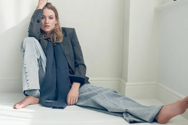 Yvonne Strahovski sitting for a studio portrait in a jacket and jeans.