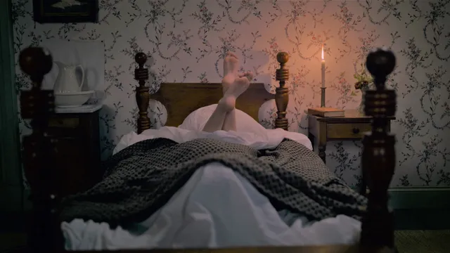 Hailee Steinfeld lying on a bed with feet raised in a screen scene.
