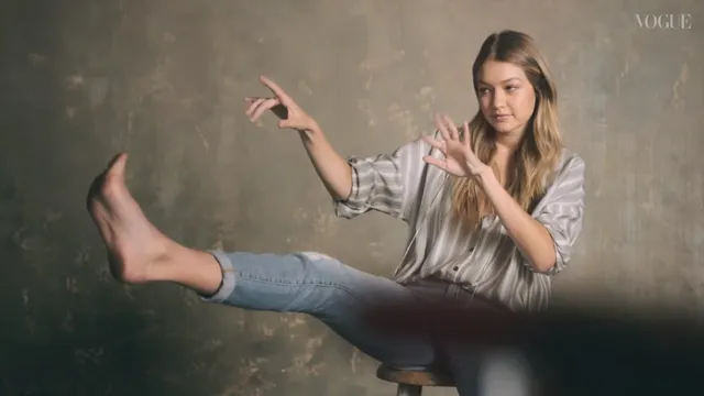 Gigi Hadid sitting in jeans with a bare foot extended during an interview.