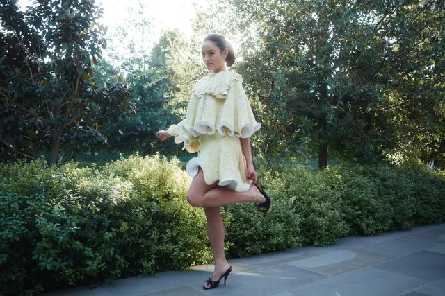 Chase Sui Wonders posing outdoors in a pale dress and black heels.