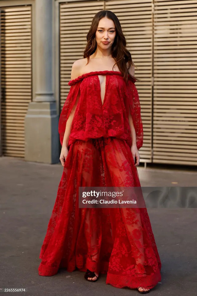 Alycia Debnam-Carey posing in a long red dress outside a venue.