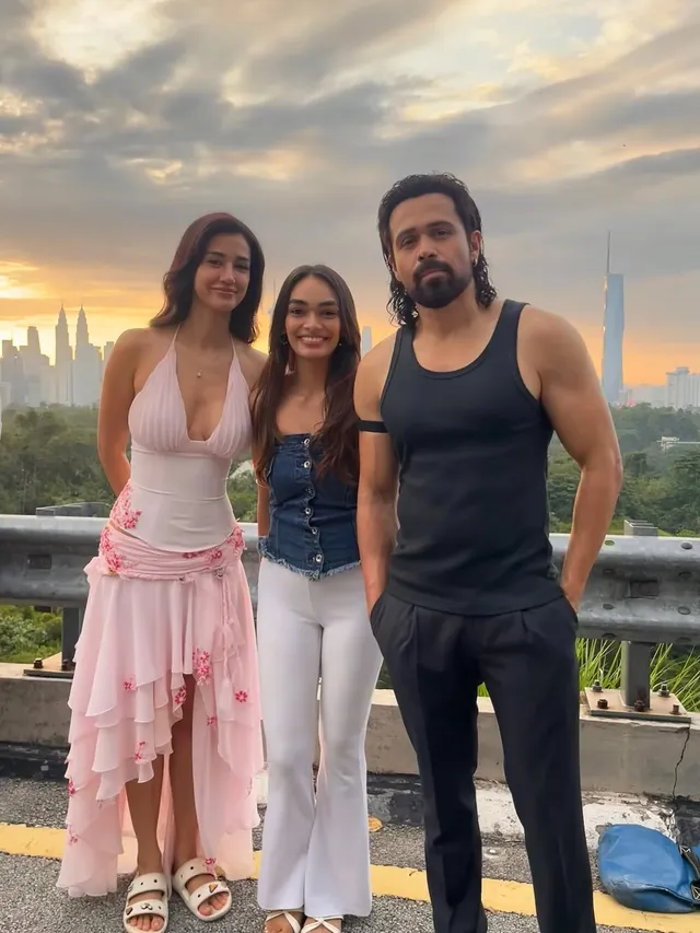 Disha Patani posing with companions in flat sandals and a pale pink dress on a terrace.