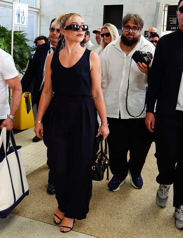 Florence Pugh walking with companions in a navy outfit and heels.