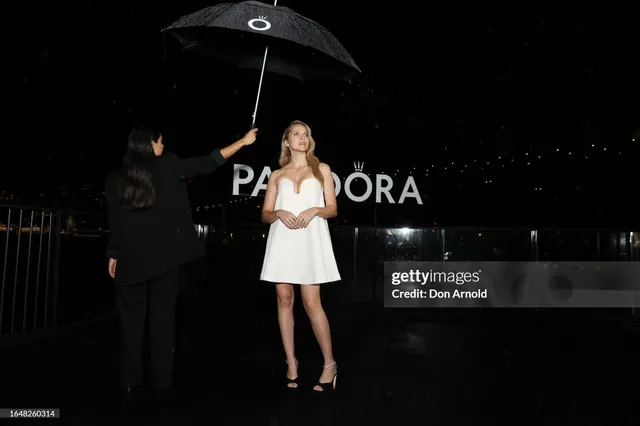 Teresa Palmer standing at an event in a white dress.