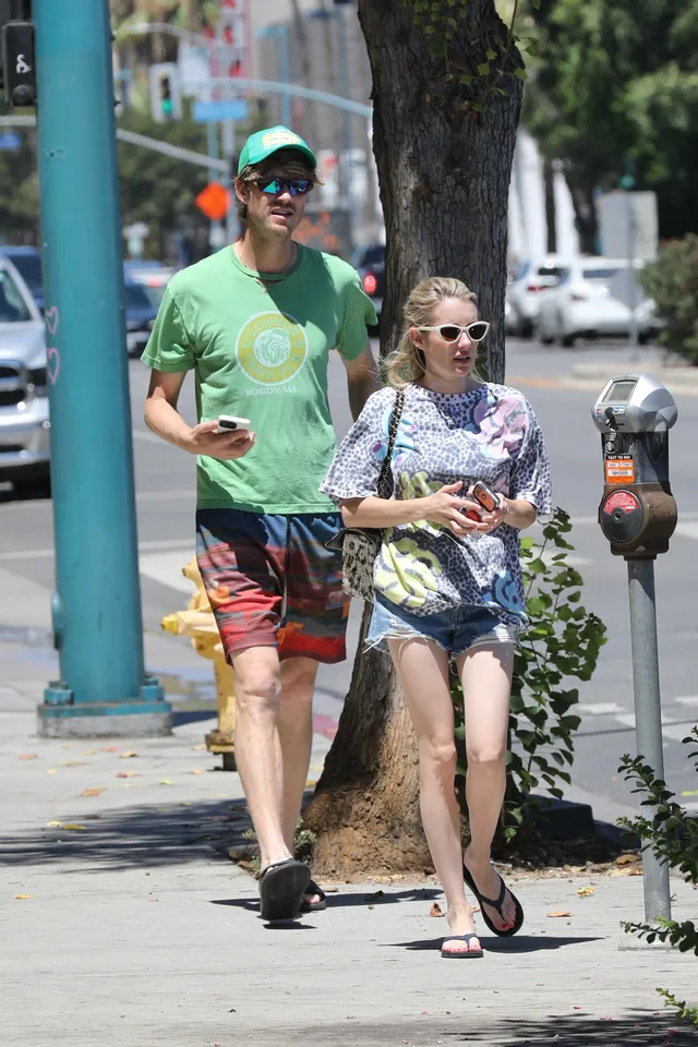 Emma Roberts walking in flat sandals beside a companion.