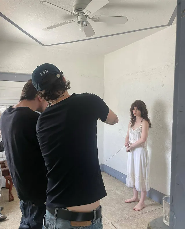 Sophie Thatcher posing barefoot in a white dress during a photo shoot.