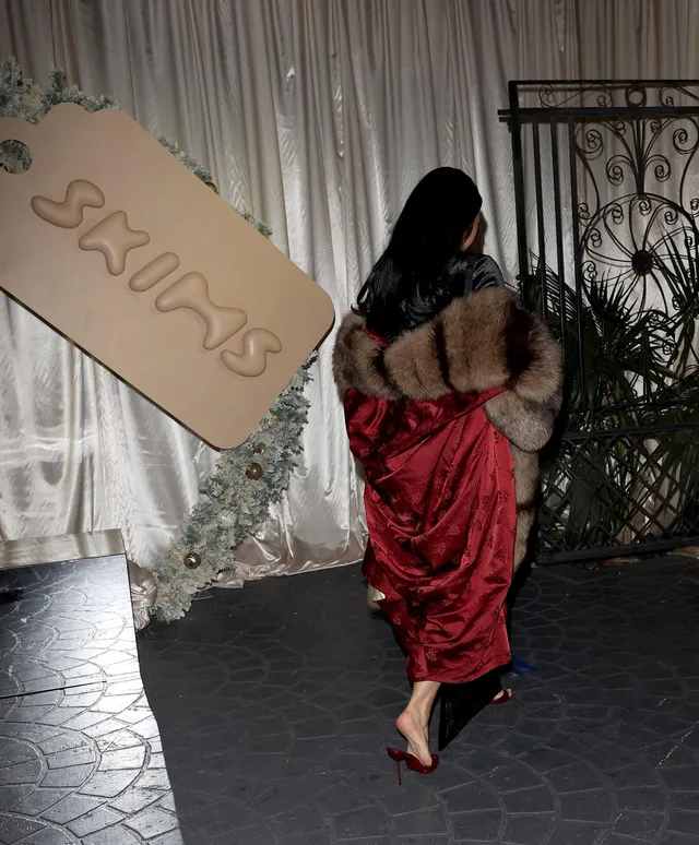Kim Kardashian: walking barefoot indoors in a red outfit.