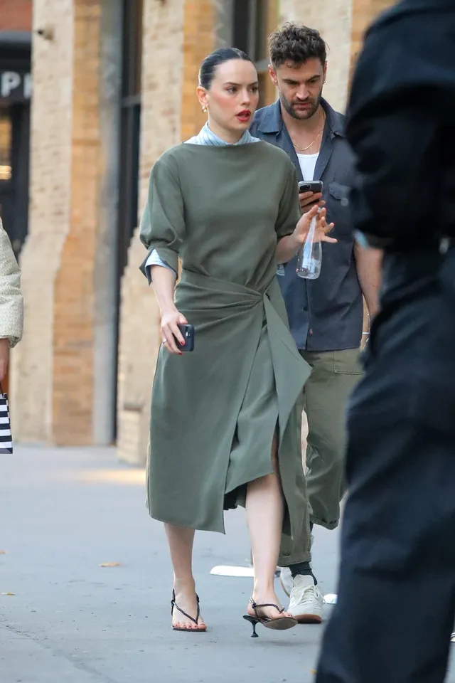 Daisy Ridley walking beside a man in a green dress.