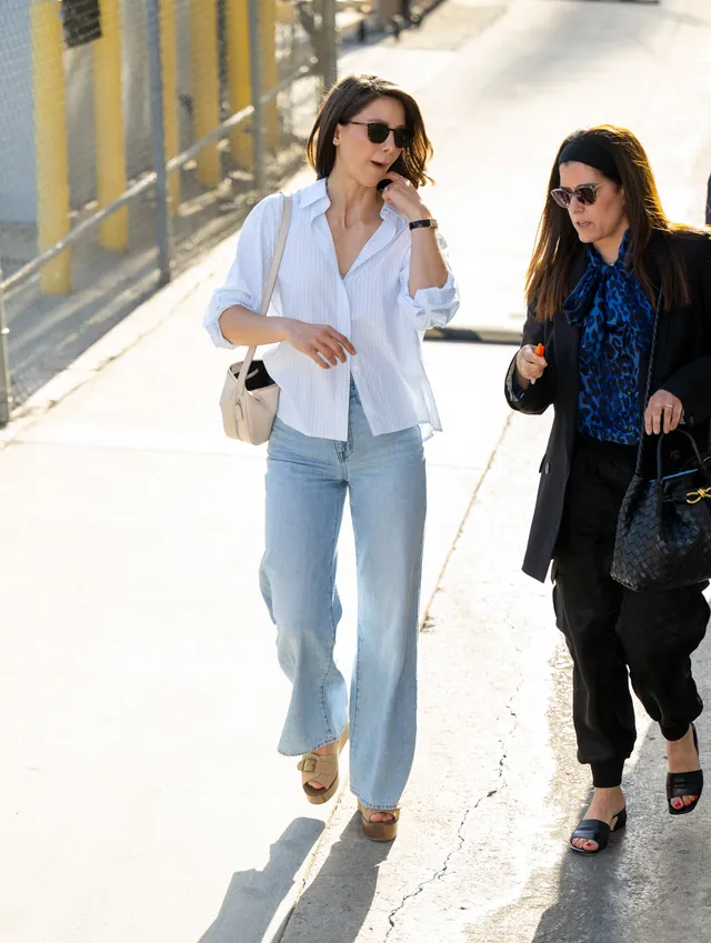 Melissa Benoist walking outdoors in jeans and tan wedge heels.