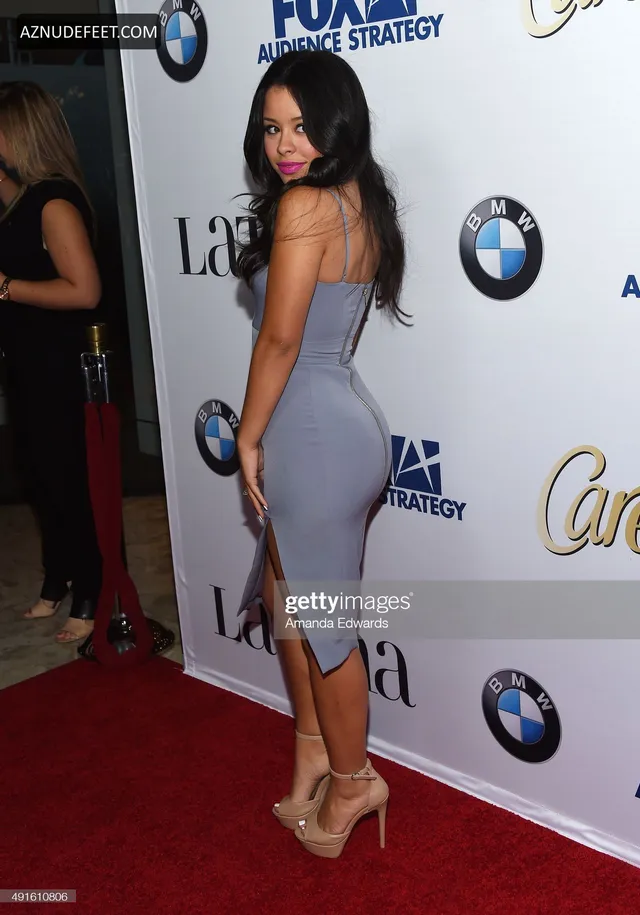 Cierra Ramirez in a gray dress and pale heels posing on a red carpet.