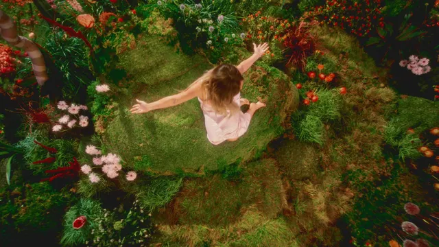 Hilary Duff standing barefoot among flowers in an overhead garden photograph.
