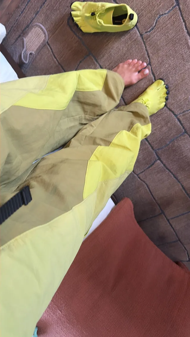 Rita Ora showing bare feet beneath bright yellow trousers.