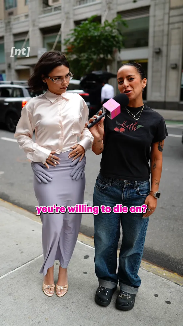 Ariana Greenblatt standing beside another person outdoors in a pale outfit and metallic heels.